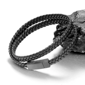 Men's double-wrap black braided leather bracelet with grey magnetic buckle on rock background