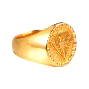 Detailed close-up of a gold signet ring with a geometric diamond pattern on a round top