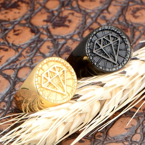 Macro shot of gold and black signet rings with diamond-shaped engraving and metal texture