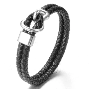 Macro detail of men's black braided double-wrap leather bracelet with silver horseshoe clasp