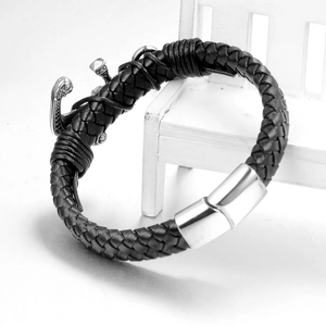 Schwarzes Lederarmband mit silbernem Anker-Anhänger und Magnetverschluss auf weißer Bank