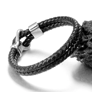 Men's black braided leather bracelet with a polished silver-tone steel clasp on volcanic rock