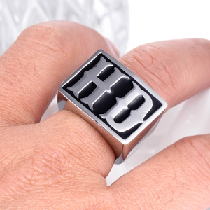 Macro detail of men's square titanium signet ring featuring gothic HB letter engraving
