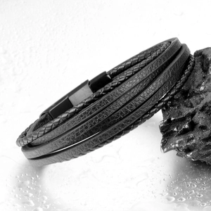 Men's multilayer black leather braided bracelet with matte steel clasp on rock