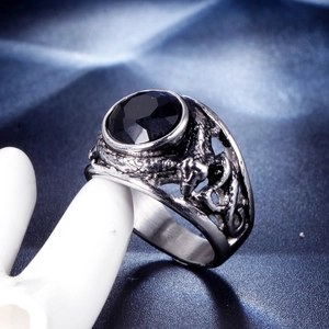 Macro shot of punk style ring with black gemstone and dragon relief on stainless steel
