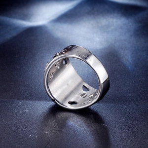 Macro shot of silver titanium steel ring featuring punk style hollow patterns and polished finish