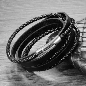 Detail of men's multi-layer black braided leather bracelet with silver magnetic metal clasp