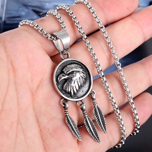 Detail of vintage punk titanium steel eagle head medallion and triple feather pendant