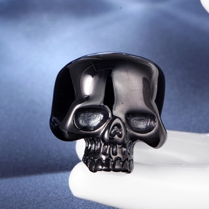 Macro shot of polished black skull ring with gothic details on a white finger display stand