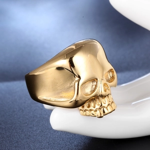 Macro detail of punk style gold skull ring with intricate skeletal carvings on a hand model