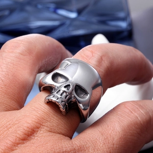 Detail view of a polished stainless steel skull ring featuring realistic bone textures