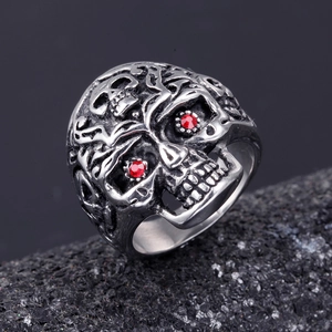 Macro shot of silver skull ring with red gemstone eyes and gothic vine engravings