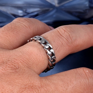 Detailed view of a silver Cuban link chain ring worn on a man's finger in punk style