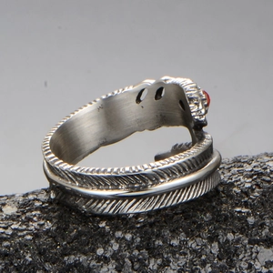 Détail d'une bague plume argentée avec gravures et petite pierre précieuse rouge