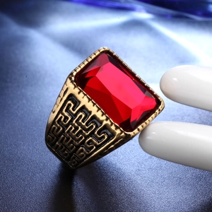 Macro detail of men's vintage gold ring with large red gemstone and Greek fret pattern