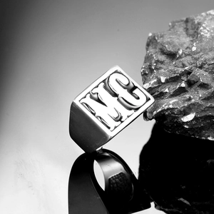 Macro shot of a square stainless steel signet ring with embossed MC letter detail