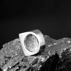 Detail of minimalist stainless steel ring with mirror finish and lava texture interior