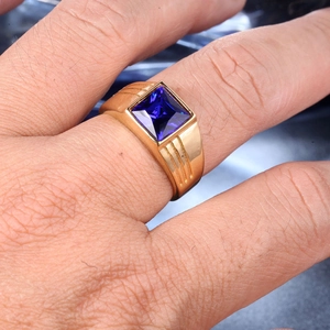 Close-up of men's gold ring with square blue gemstone and side groove detailing