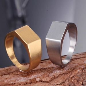 Brushed stainless steel signet rings in gold and silver finish on wood base