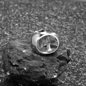 Polished titanium steel skull ring for men displayed on a natural dark mineral stone