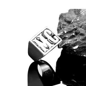 Vintage stainless steel signet ring with engraved MC letters for men on black rock base