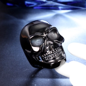 Detailed view of punk style black stainless steel skull ring with polished finish on display