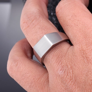 Detailed close-up of a matte silver titanium signet ring worn on a finger