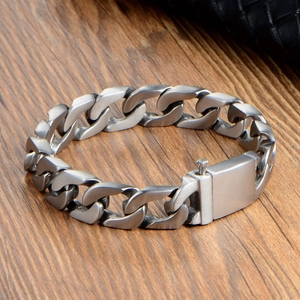 Flat Cuban link bracelet in matte silver titanium steel on a rustic wooden background