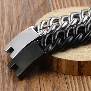 Men's thick Cuban chain bracelet in silver and black finish on a rustic wooden base