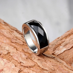 Detailed view of stainless steel ring with rectangular black gem on rustic wood texture