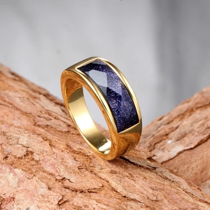 Detail of gold-plated stainless steel ring with blue sandstone inlay on natural wood