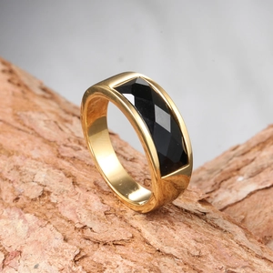 Macro shot of polished gold stainless steel ring featuring a rectangular black faceted stone