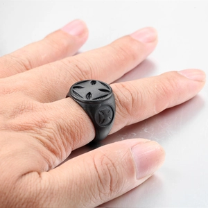 Macro view of matte black stainless steel signet ring with engraved cross relief pattern