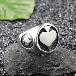Close-up of rock punk King of Spades ring on textured stones with a green leaf accent
