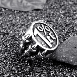 Macro shot of 1%er engraved steel biker ring with claw-like texture on black rocks