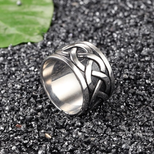 Detailed close-up of a wide stainless steel ring with Celtic knot patterns on dark stones