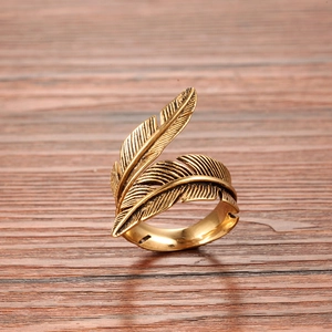 Bague plume vintage en acier titane doré avec détails antiques sur fond en bois