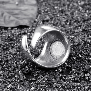Bague ouverte en acier titane poli au design courbé minimaliste sur une surface en pierre