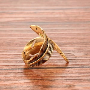 Bague plume vintage en acier inoxydable doré poli présentée sur un support en bois