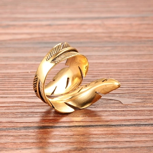 Gros plan d'une bague plume dorée avec finition mate vintage sur fond en bois