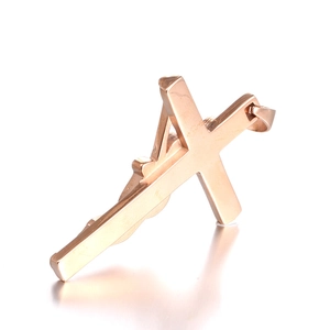 Macro shot of rose gold titanium cross pendant with Jesus relief on reflective surface