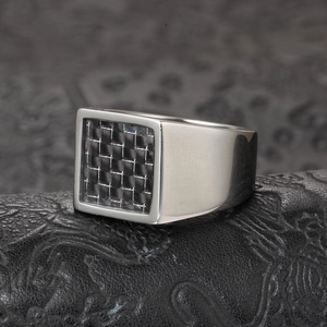 Mens square titanium steel ring with black carbon fiber inlay on a leather surface