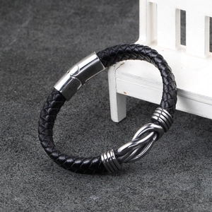 Detail of black braided leather bracelet with silver knot element and magnetic steel clasp