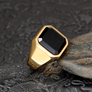 Detailed close-up of a men's gold stainless steel ring with a large black gemstone