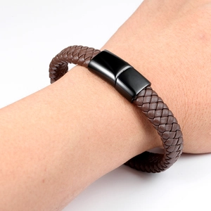 Detail of hand-woven brown leather bracelet with sleek black magnetic steel clasp