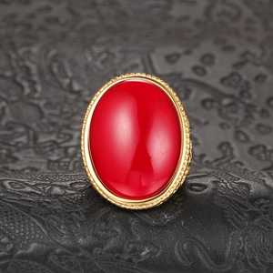 Oval red agate titanium steel ring with gold twisted rope edge on leather background