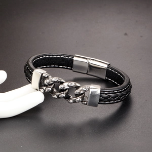 Dettaglio del bracciale in pelle intrecciata nera con catena a teschi e chiusura magnetica