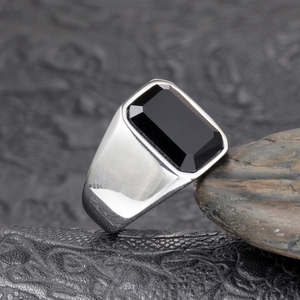 Macro detail of men's vintage stainless steel signet ring with black faceted gemstone