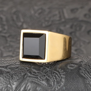 Gros plan sur une bague homme en titane doré sertie d'une pierre noire carrée