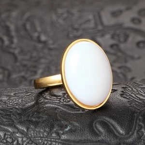 Détail macro d'une pierre ovale blanche sertie sur une bague en acier titane doré poli